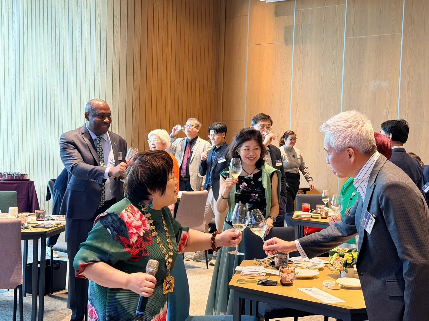 President Windy Yang, wearing the chain of office, raising a toast with members